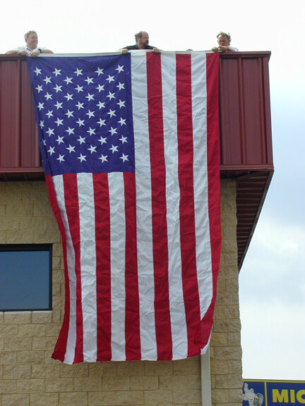 Bill Strang, Jay Marion and an unknown helper secured this large flag to the building on September 12, 2001.